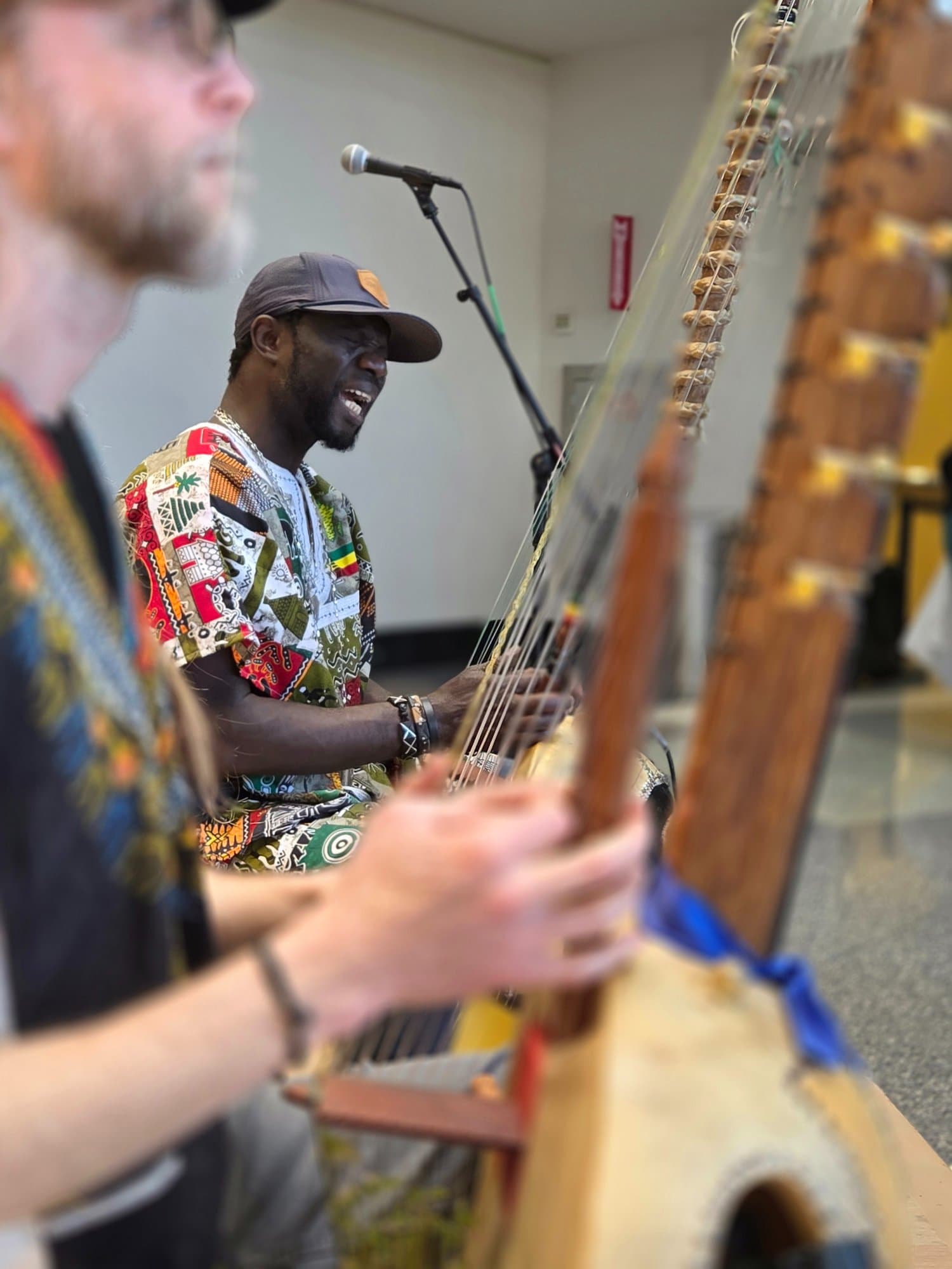 West African kora player performing with another musician in the foreground — documenting the breadth of the M.O.M. artist roster